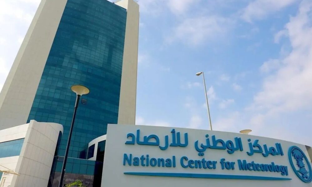 Facade of the National Center for Meteorology with a blue glass tower and a large sign in Arabic and English in front of the building.