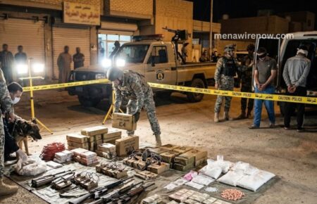 Night scene of a police raid: seized weapons and packages laid out on cloth, officers in tactical gear securing the area behind yellow caution tape.